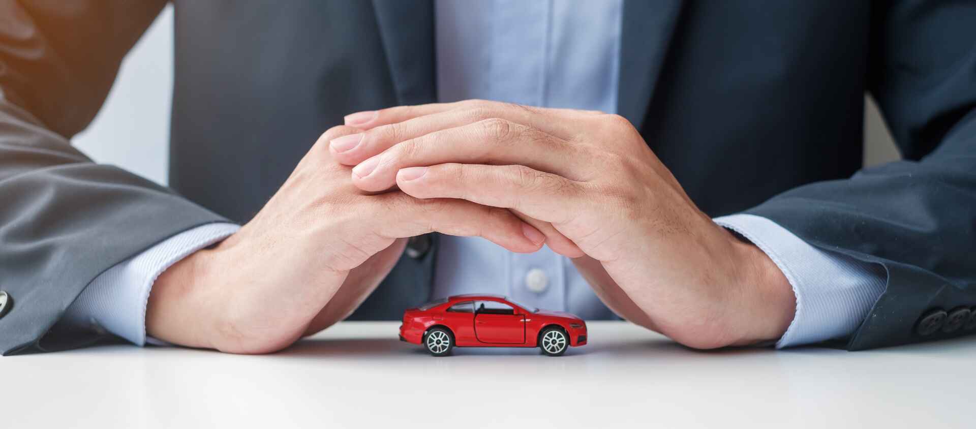 Businessmen covering red car with hand. Concept of car insurance management system.